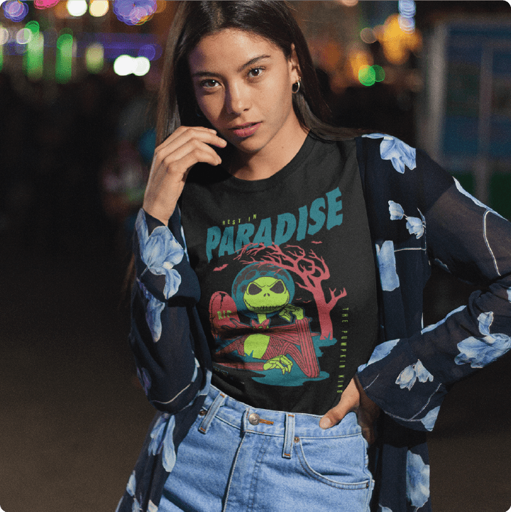 Young Lady wearing a black high waisted shirt with a cartoon skeleton character and 'Rest in Paradise' text at a carnival at night