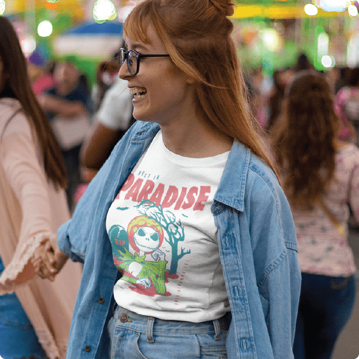 Woman wearing a white high waisted shirt with a skeleton graphic and text, standing in a crowded area.