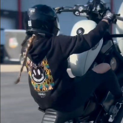 Person performing a wheelie on a motorcycle in an open area with text overlay.