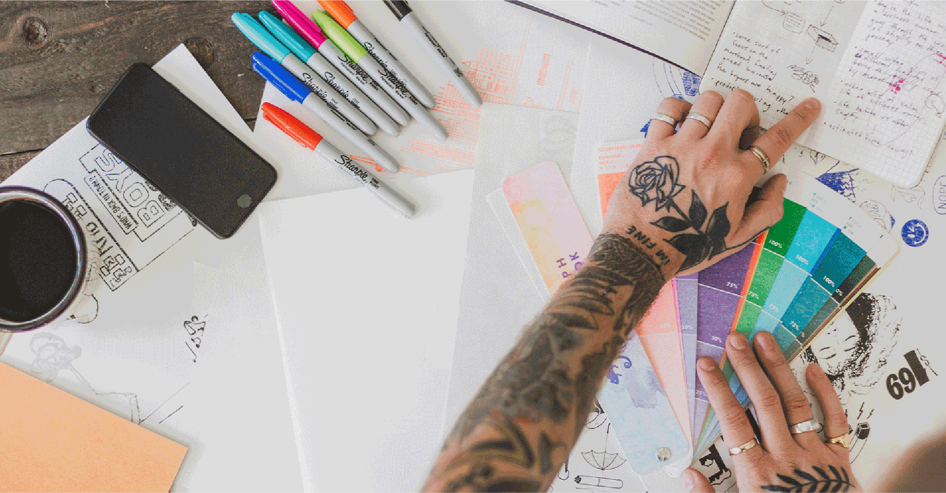 intro header image of an artists tattooed hand working at his work station