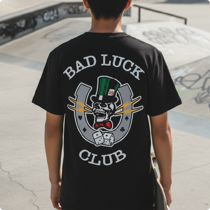 Rear view of a young man wearing a black High Roller t-shirt outside at a skatepark.