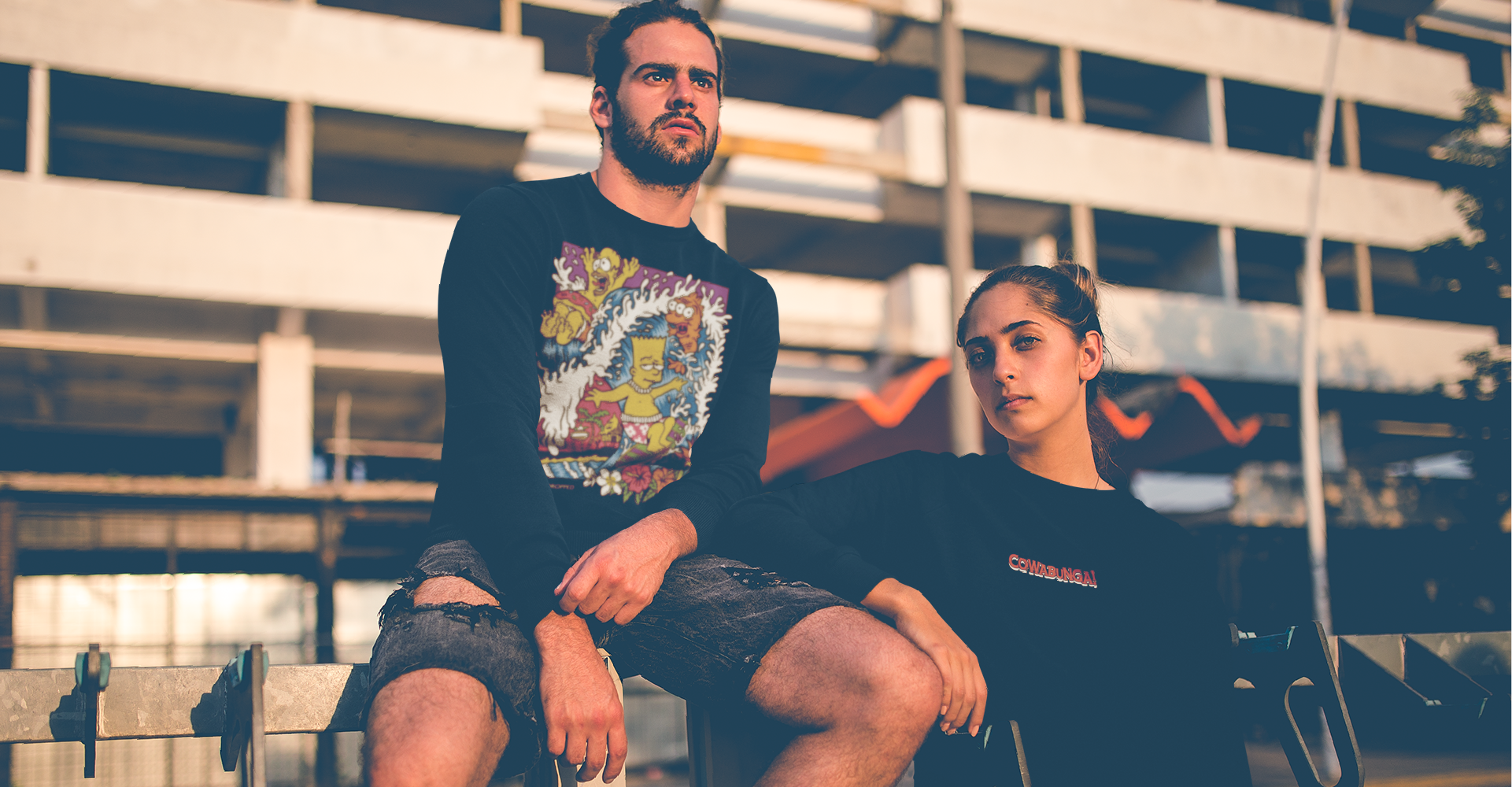 man and woman posing in front of a parking garage wearing bart simpson inspired long sleeve t shirts
