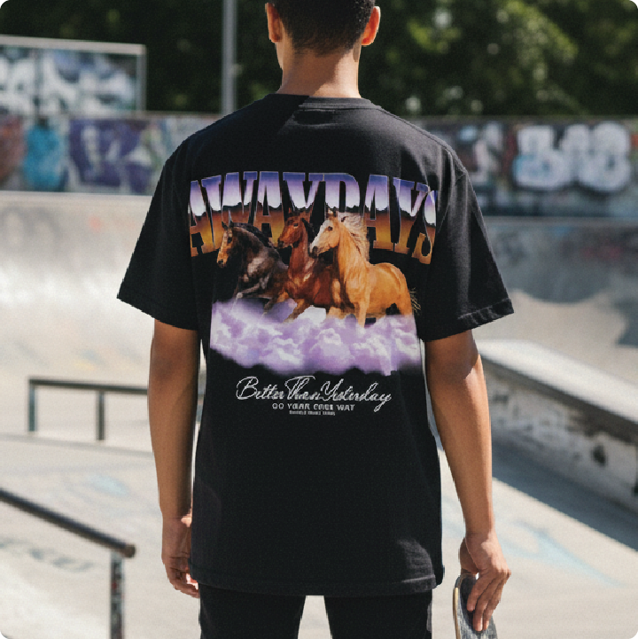 rear view of a young man wearing a black away days t-shirt at a skatepark.