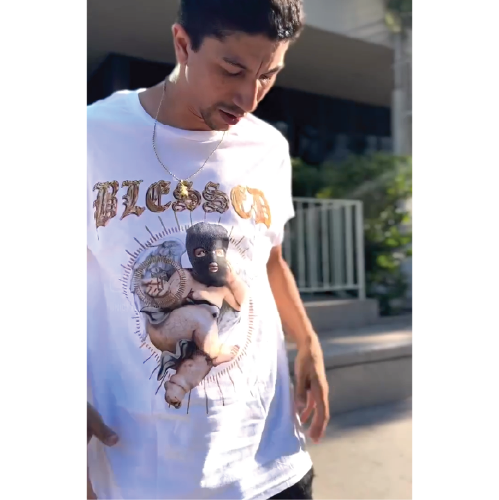 Pro skateboarder Nick Tucker, wearing a white Blessed shirt in front of a skate park.