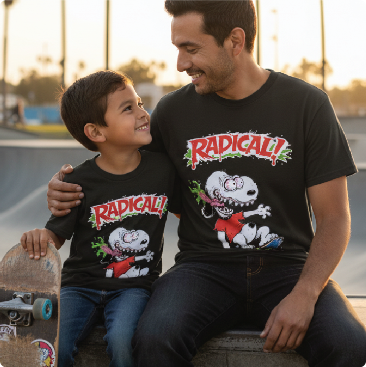 Father and son sitting together wearing black Snoop Roth t-shirts with 'Radical!' graphic design at a skate park.