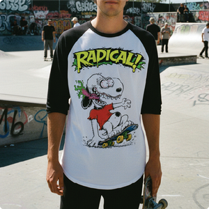 Person wearing a t-shirt with a snoopy rat fink cartoon character and 'Radical!' text at a skate park.