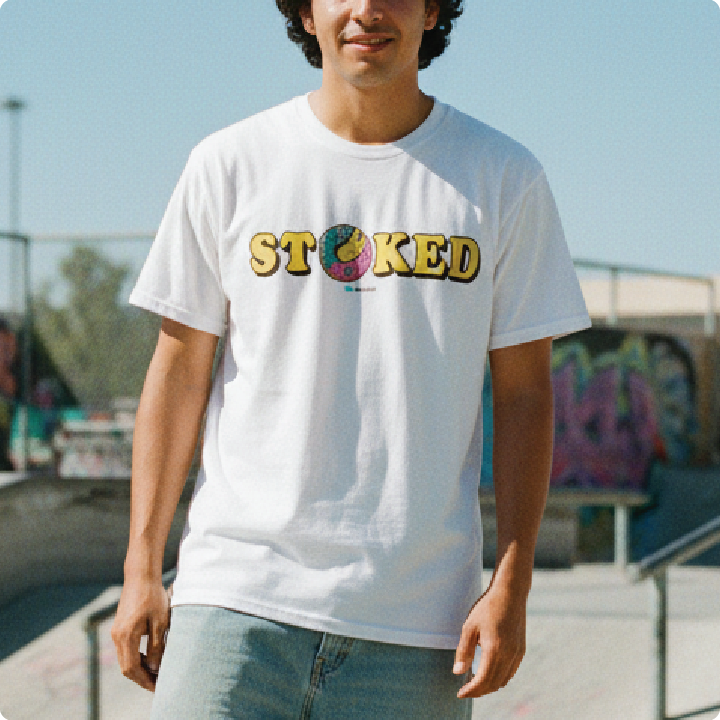 Front view of a man wearing a white 'STOKED' t-shirt at a skatepark.