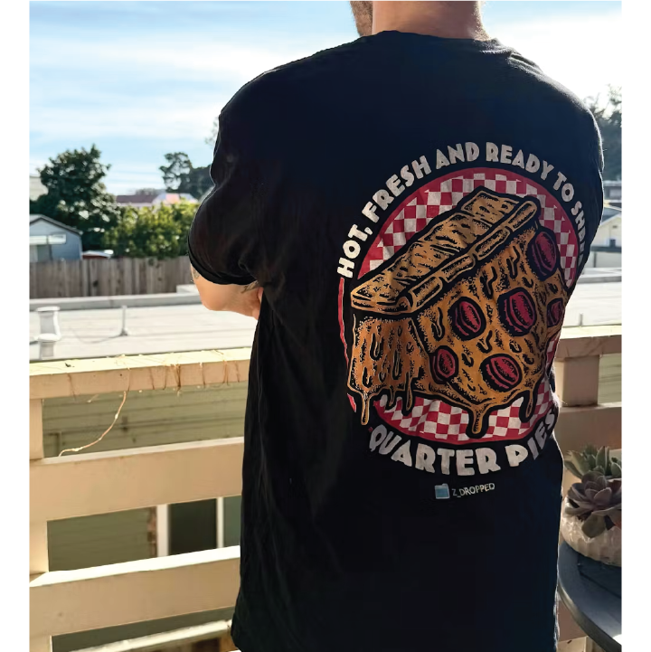 Rear view of a person wearing a black quarter pies t-shirt with a pizza quarter pipe graphic and text standing on a balcony.