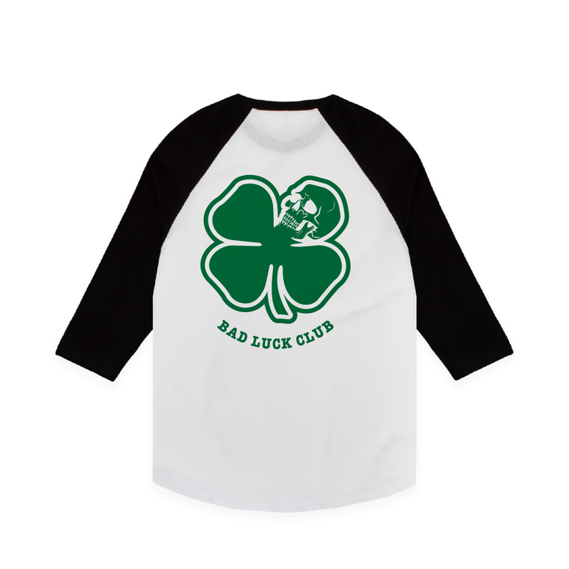 Rear view of a black and white raglan t-shirt with a large green skull clover design with green 'Bad Luck Club' text.