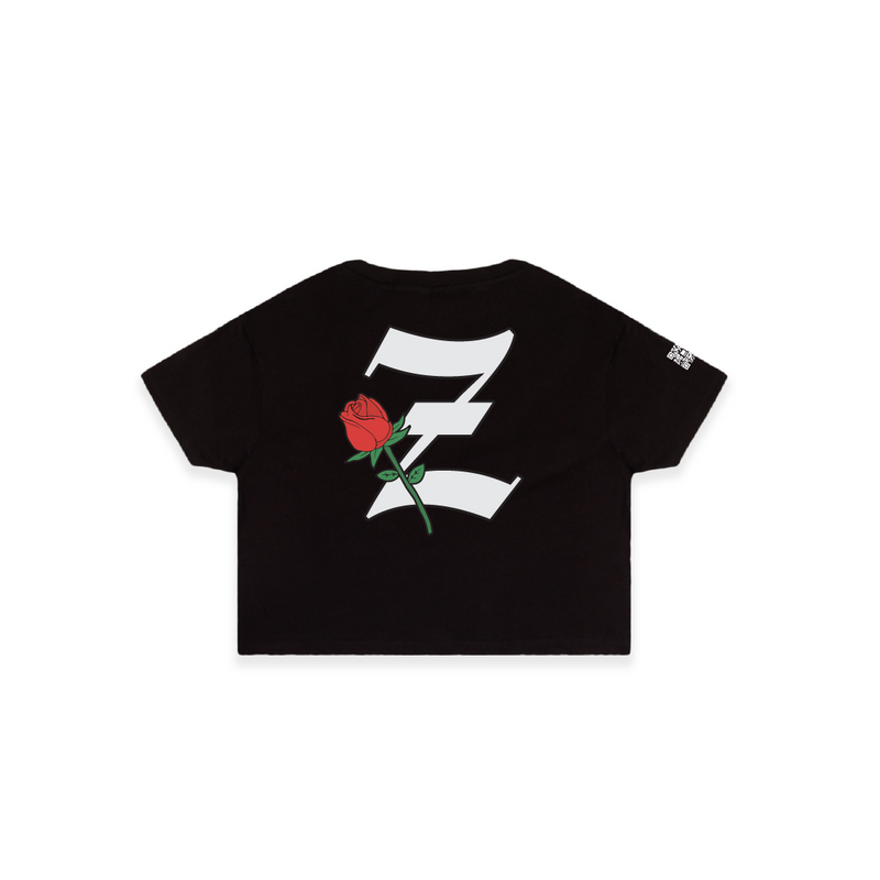 Rear view of a womens black crop top t-shirt with a large white 'Z' logo and red rose flower on a white background