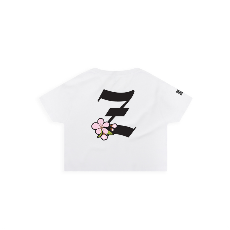 Rear view of a women's white crop top t-shirt with a large black 'Z' logo and pink cherry blossom flower on a white background
