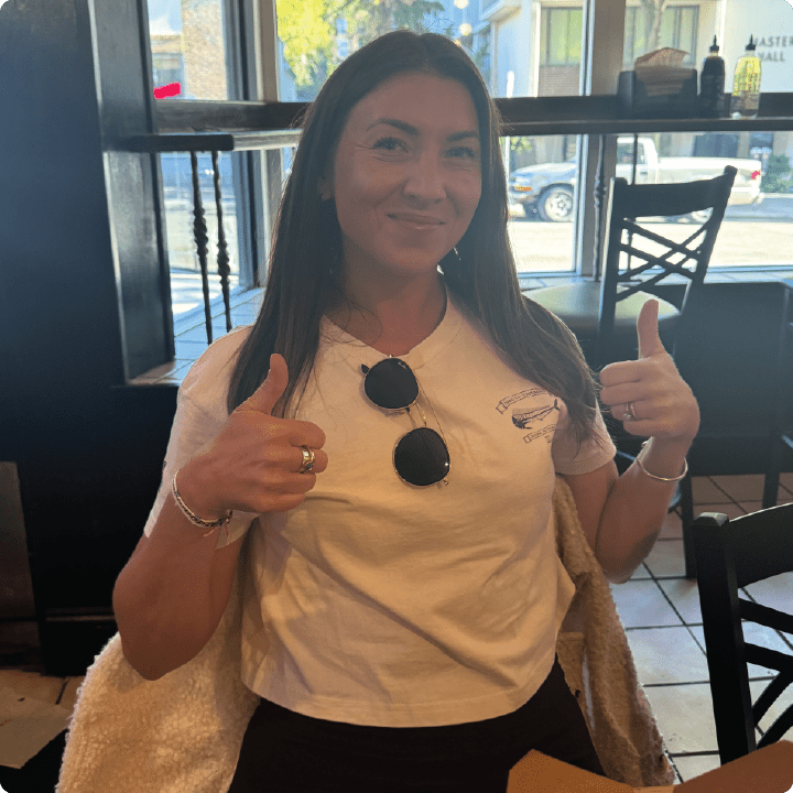 Woman giving a thumbs-up gesture in a casual setting