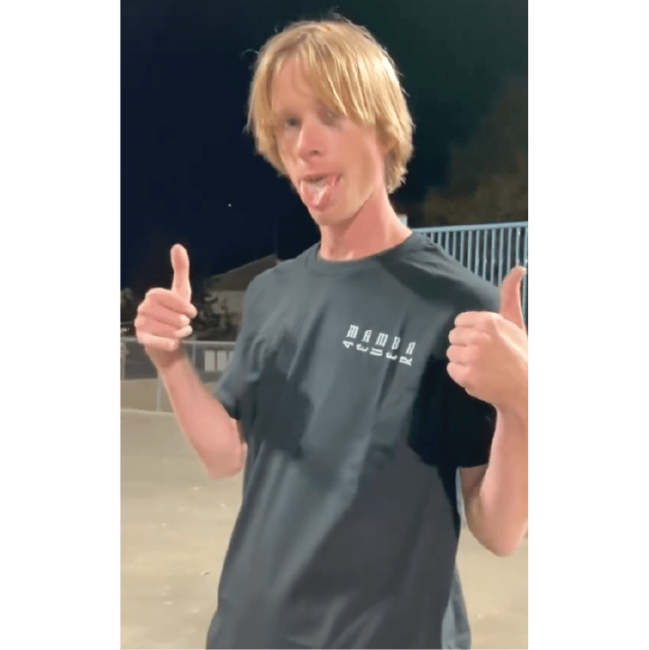 Pro Skateboarder Jeff Dechesare wearing a black mamba t-shirt, giving a thumbs-up gesture outdoors.