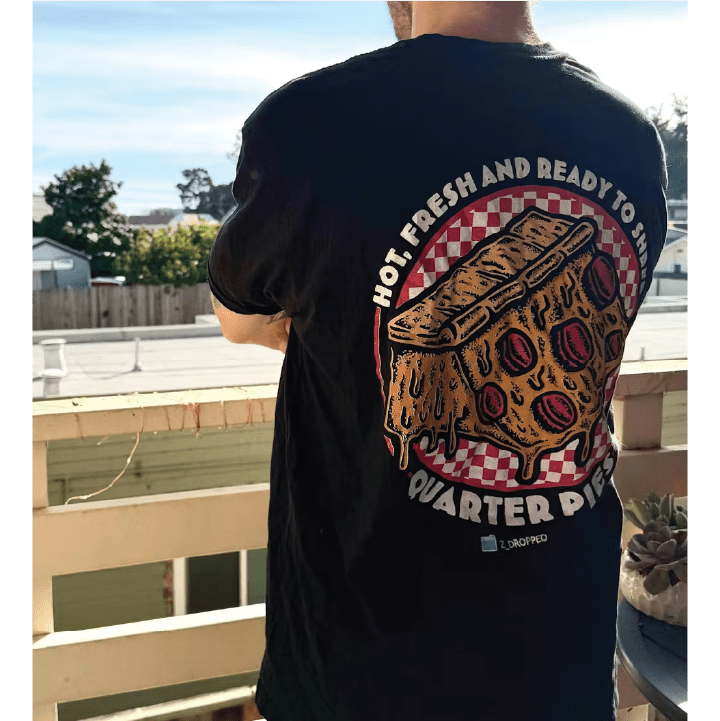 Rear view of a person wearing a black quarter pies t-shirt with a pizza quarter pipe graphic and text standing on a balcony.