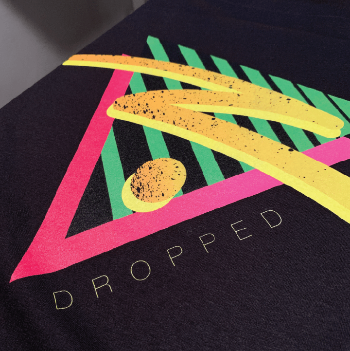 Close up print detail of a Black t-shirt with colorful geometric design and 'ZDROPPED' text