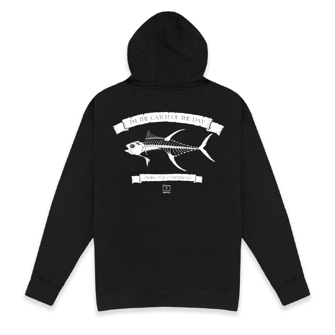 Rear view of a unisex black hoodie with large white tuna bones graphic on a white background with white text that reads "I'm the catch of the day" on the top of the fish graphic and "fishing for compliments" in white text below the graphic