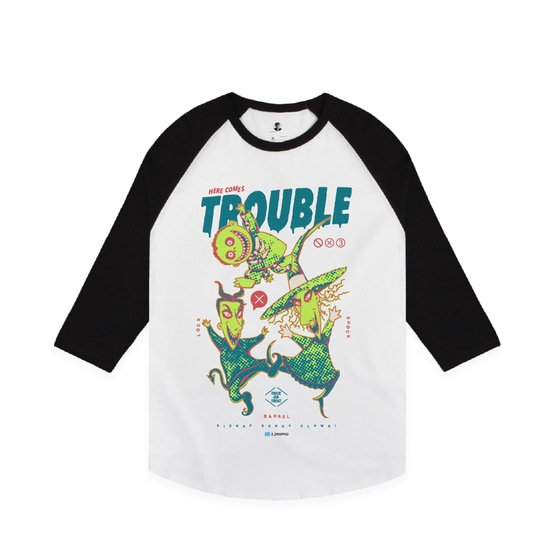 Front view of a white and black baseball tee with colorful lock shock and barrel and 'Here Comes Trouble' text on a white background