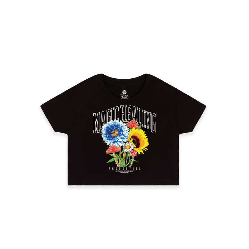 Front view of a women's black crop top shirt with flowers psychedelic mushrooms and large white 'MAGIC HEALING' text.