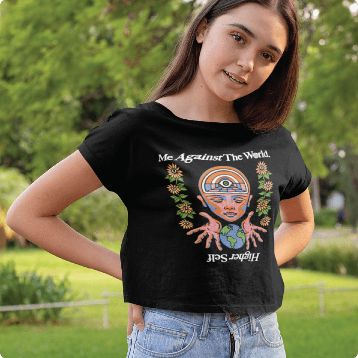 Person wearing a black crop top t-shirt with a colorful design on the front in an outdoor setting