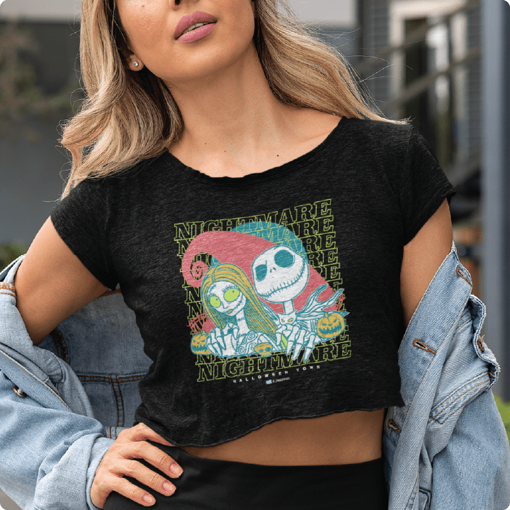 Young woman wearing black crop top with neon green cartoon skeleton and 'NIGHTMARE' text.