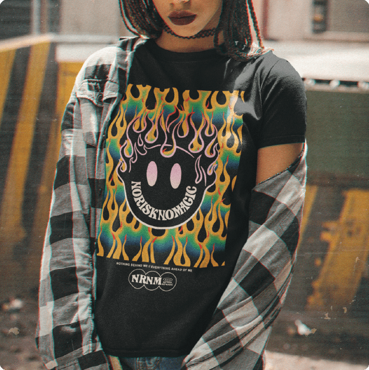 A woman wearing a black t-shirt with a colorful flaming smiley face graphic and plaid shirt.