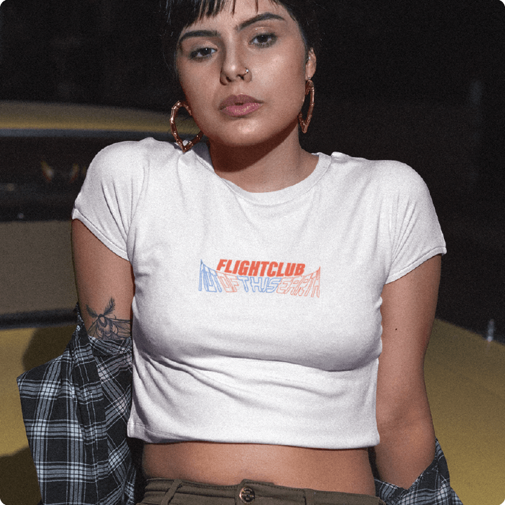Person wearing a white crop top t-shirt with 'FLIGHT CLUB' text, sitting outdoors.