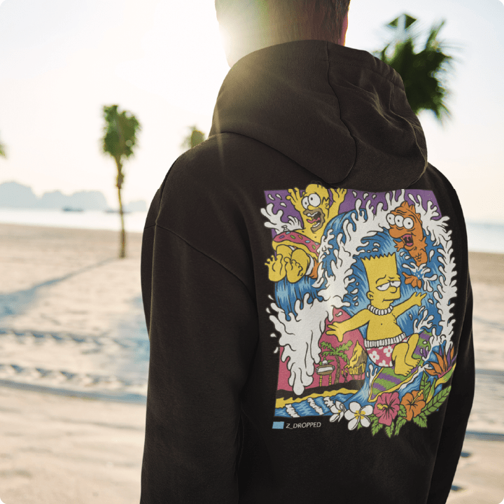 Person wearing a unisex black hoodie with Bart and Homer Simpson surfing a wave standing on a beach.