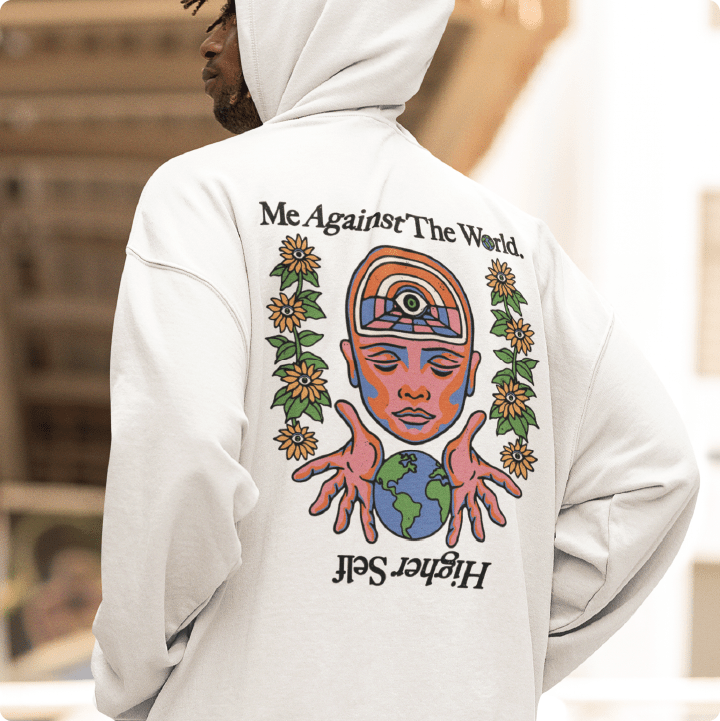 Young man wearing a unisex white hoodie with black 'Me Against The World Higher Self' text in an urban setting.