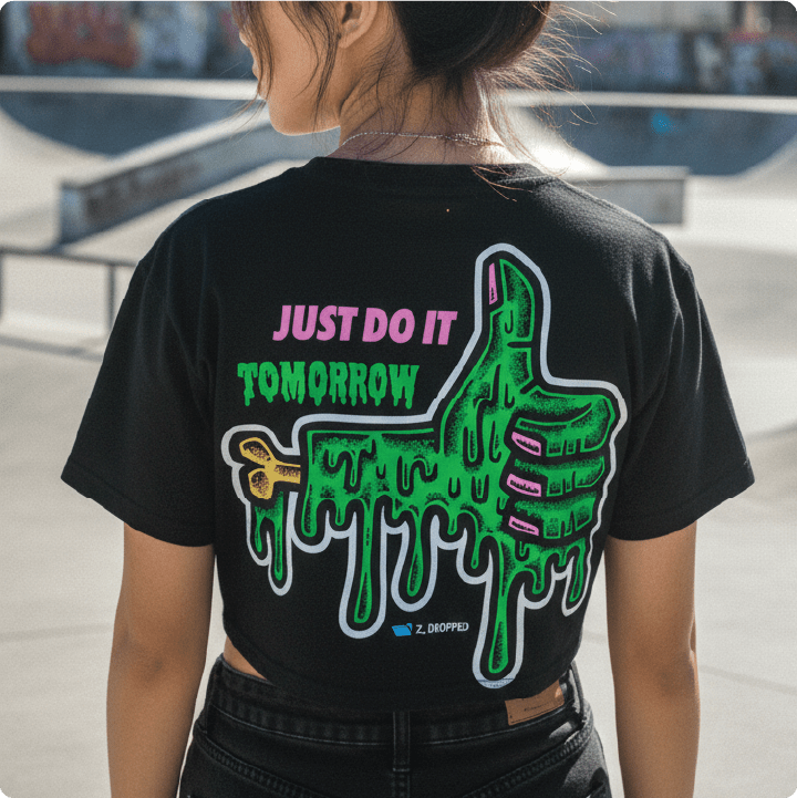 Young woman wearing a black t-shirt with a green slimy thumbs up graphic and text at a skate park.