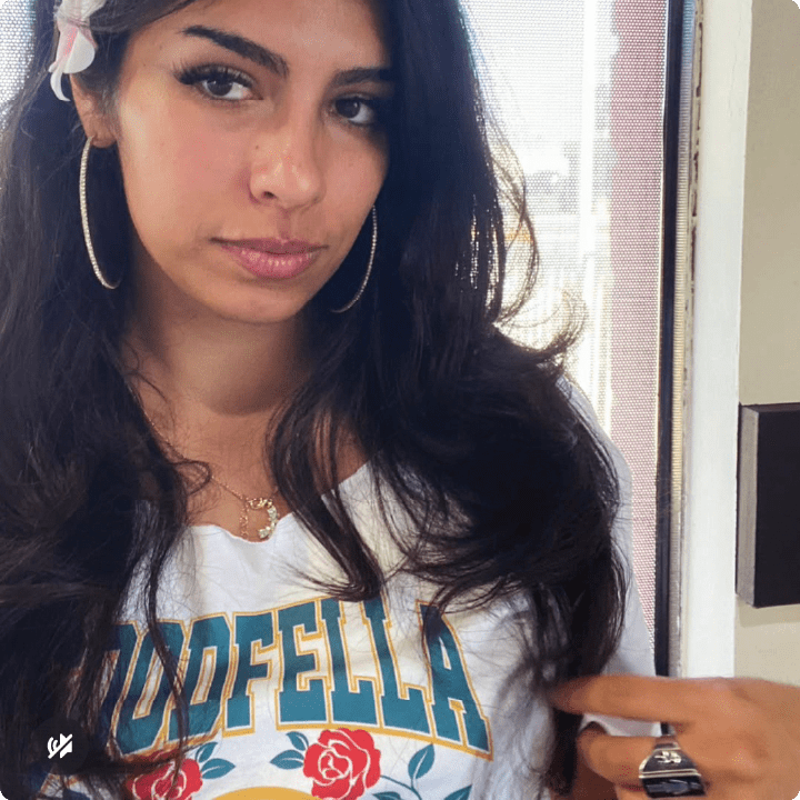 Young woman taking a selfie, wearing a 'GOODFELLA' white crop top at a diner.