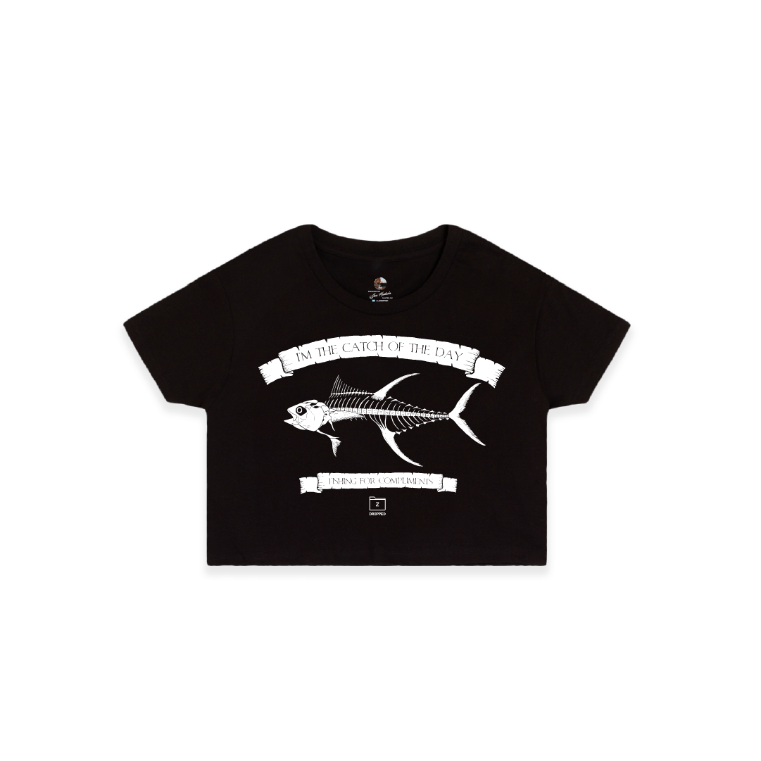 Front view of a womens black crop top t-shirt with a large white tuna bones fish and 'catch of the day' text on a white background