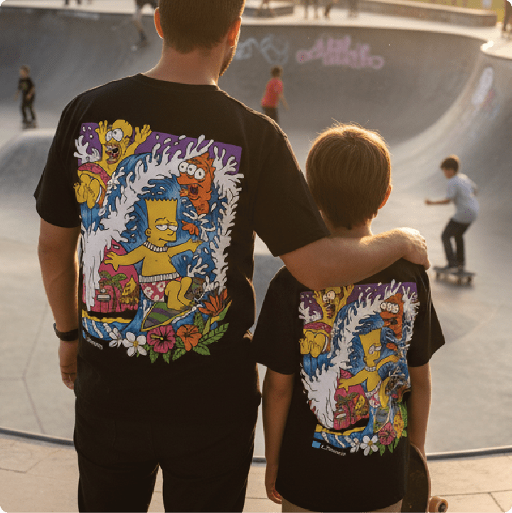 Rear view of a father and son wearing black bartsunami t-shirts at a skate park.