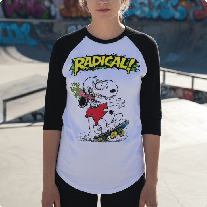 Person wearing a black and white baseball shirt with a snoopy rat fink cartoon character and 'Radical!' text at a skate park.