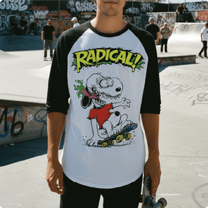 Person wearing a t-shirt with a snoopy rat fink cartoon character and 'Radical!' text at a skate park.