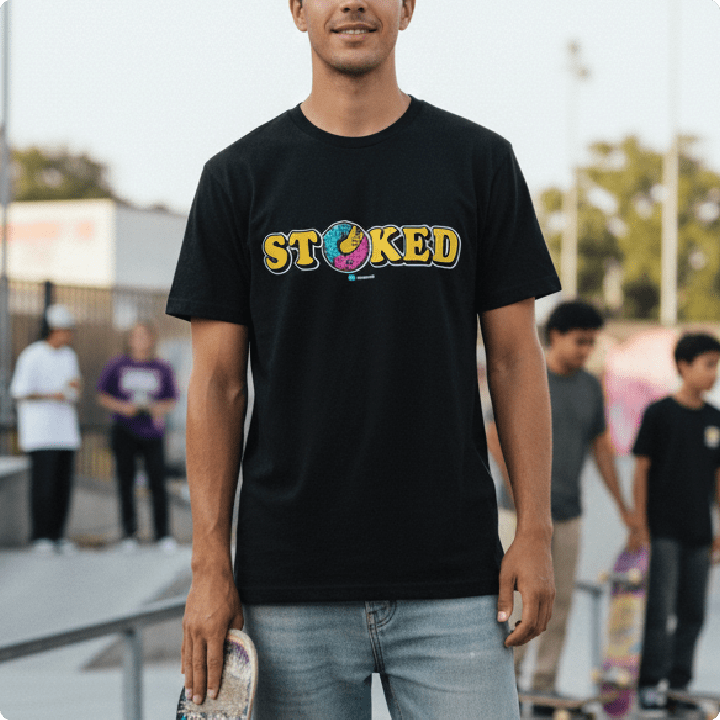 Front view of a man wearing a black 'STOKED' t-shirt at a skatepark.
