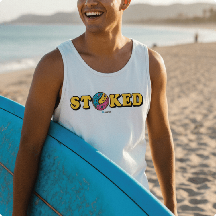 Surfer holding a surfboard in a white 'STOKED' tank top at the beach.