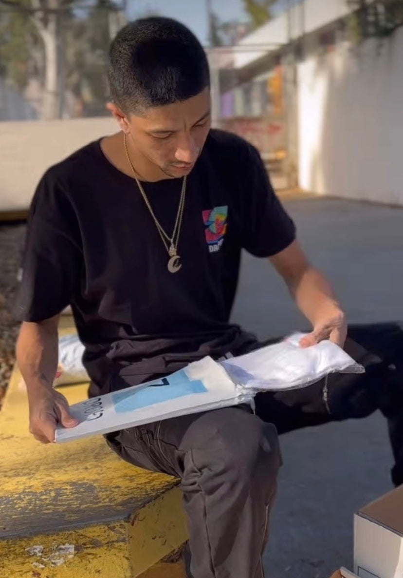 Professional skateboarder Nick Tucker opening a zdropped package on a skate bench.
