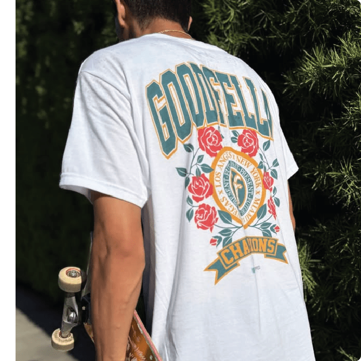 Rear view of pro skateboarder nick tucker wearing a white t-shirt with 'Goodfella' design, holding a skateboard.