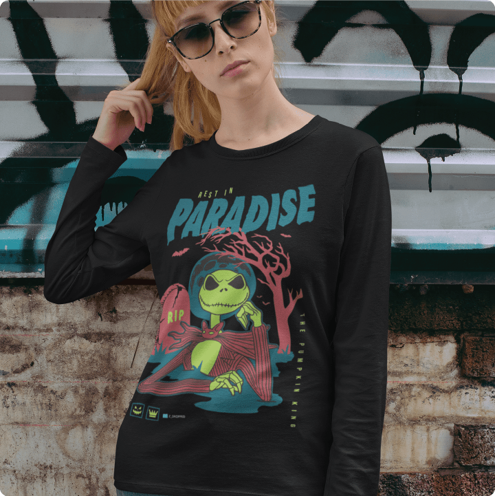 Young lady wearing a black long-sleeve shirt with a colorful graphic in front of a graffiti-covered wall.