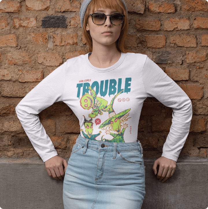 Person wearing a white long-sleeve shirt with a Halloween graphic and text, standing against a brick wall.