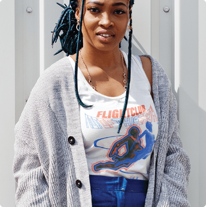 Woman wearing a 'Flight Club' men's tank top, standing against a light-colored wall.