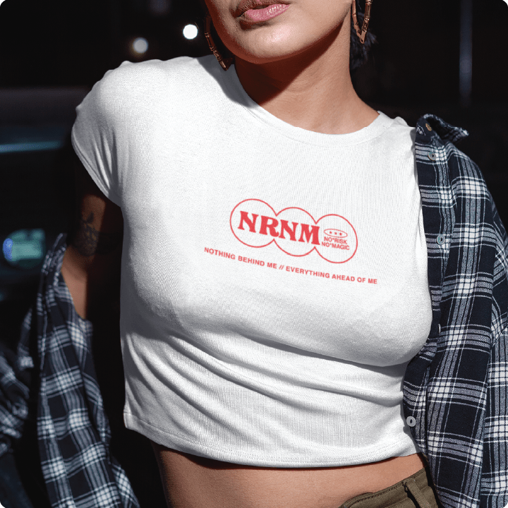 Person wearing a white t-shirt with 'NRNM' logo and text, standing outdoors.