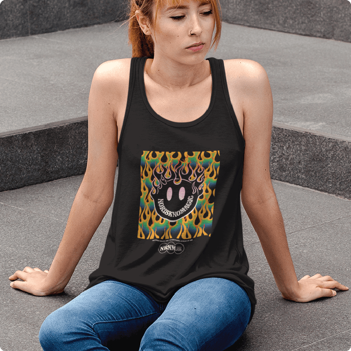 Woman wearing a black tank top with a colorful flaming smiley face graphic  sitting on steps.